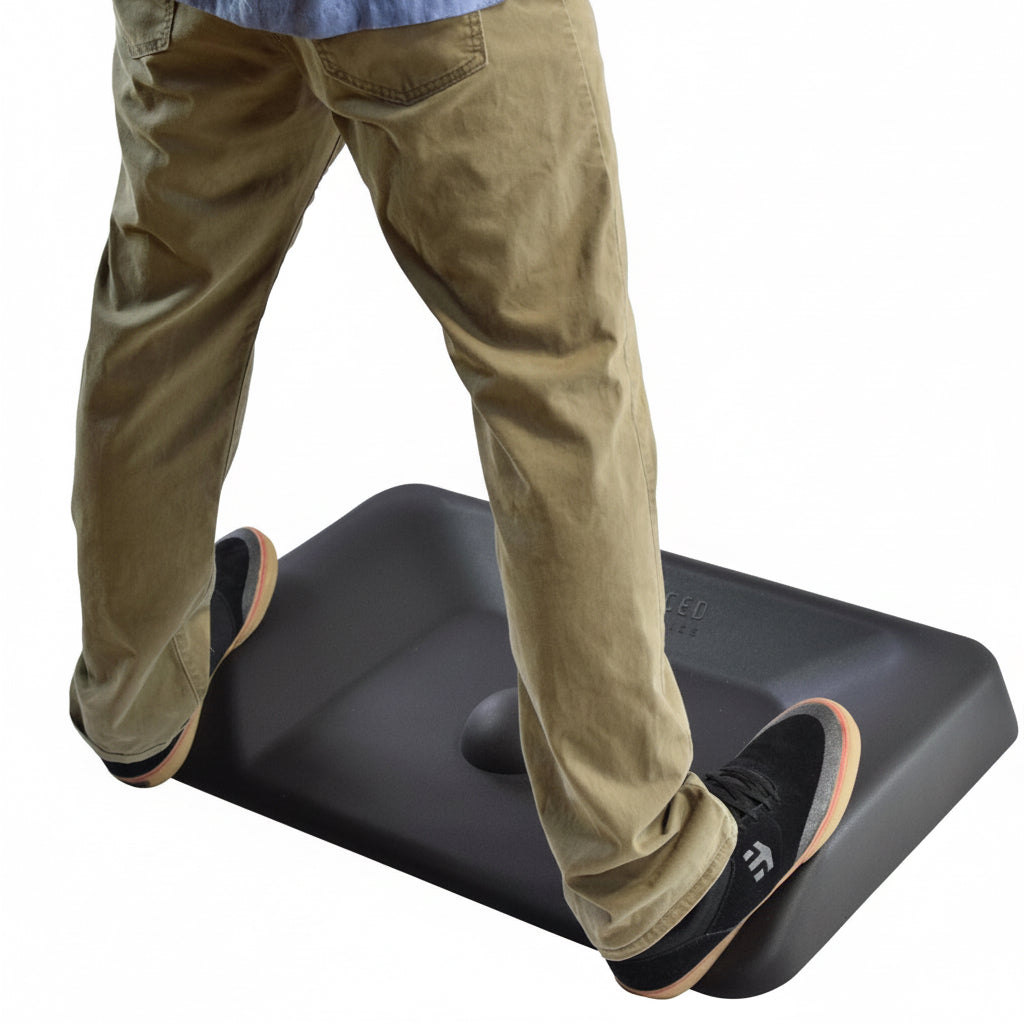 Man standing on black anti-fatigue mat at standing desk showing wide stance